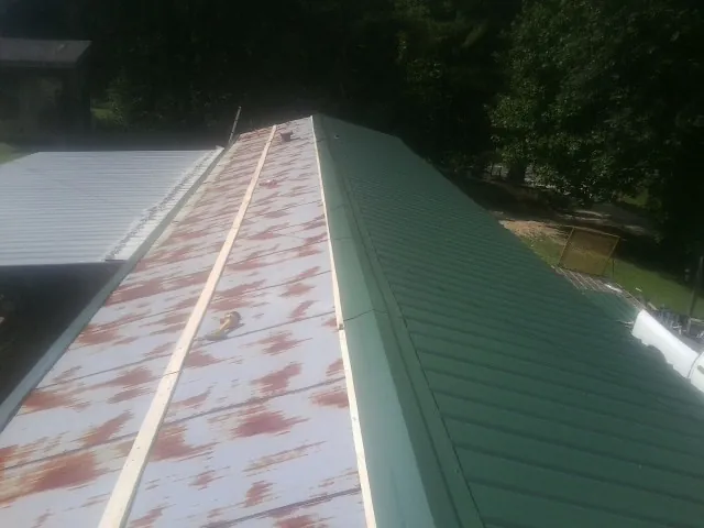 Old rusted panels beside newly installed green metal roofing — Wind Damage Roof Repair by Roofing Brothers in Hahira