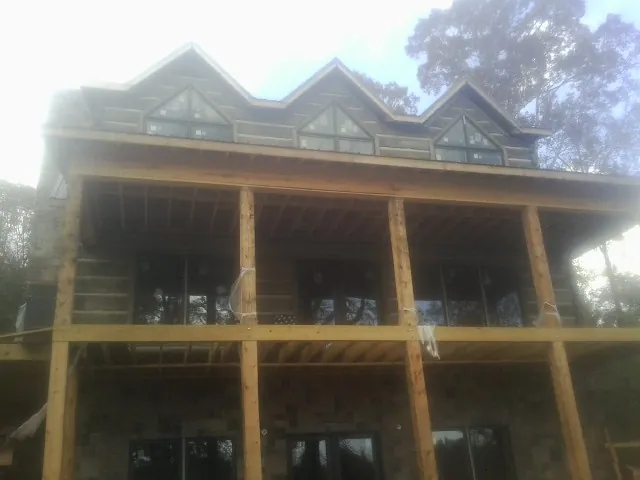 Dormers and porch framing on a large log home under construction — Roof Coating work by our crew in Hahira