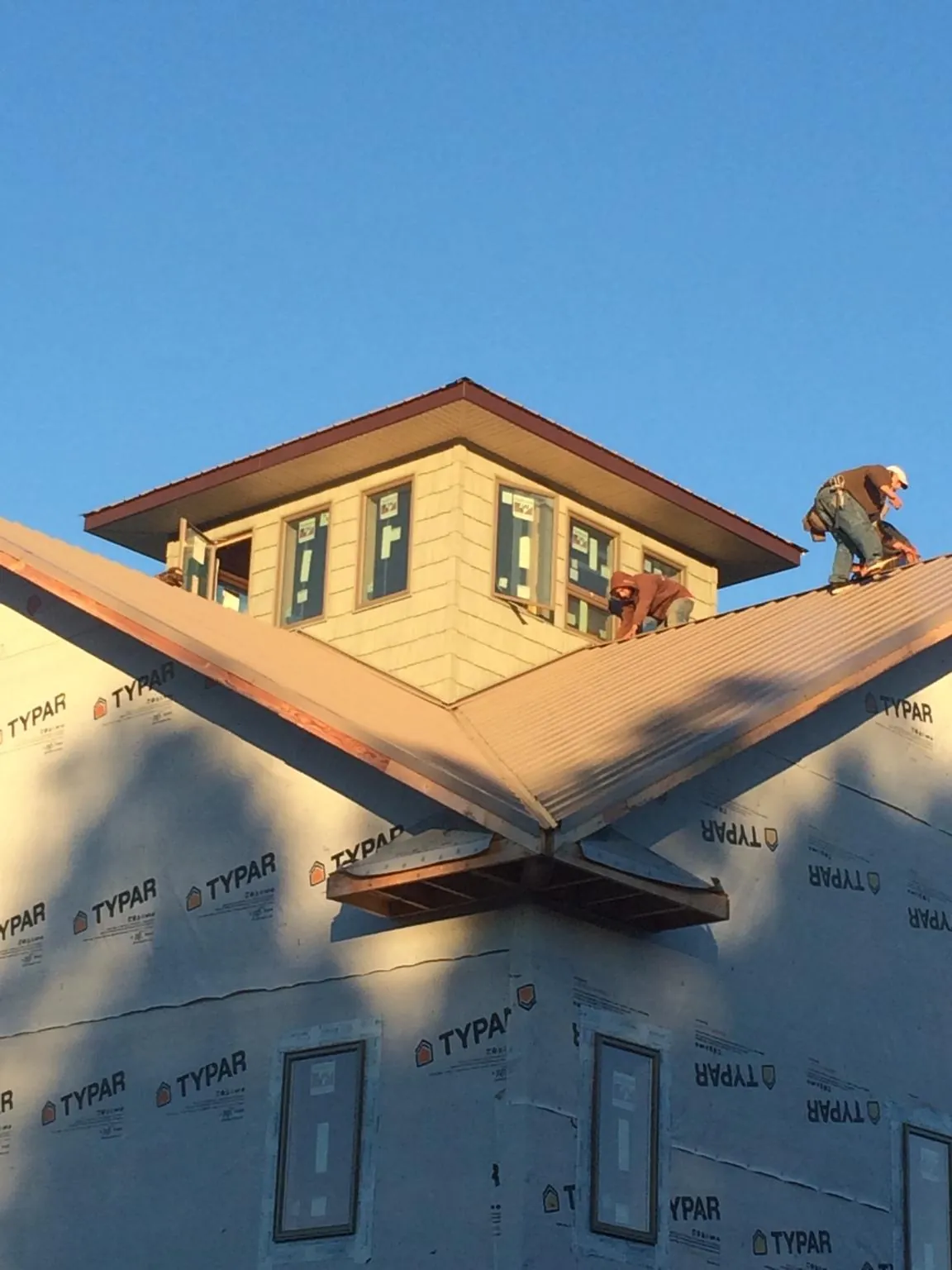 Roofers working around a rooftop cupola on a new metal roof at sunset — Roof Waterproofing in Hahira by Roofing Brothers
